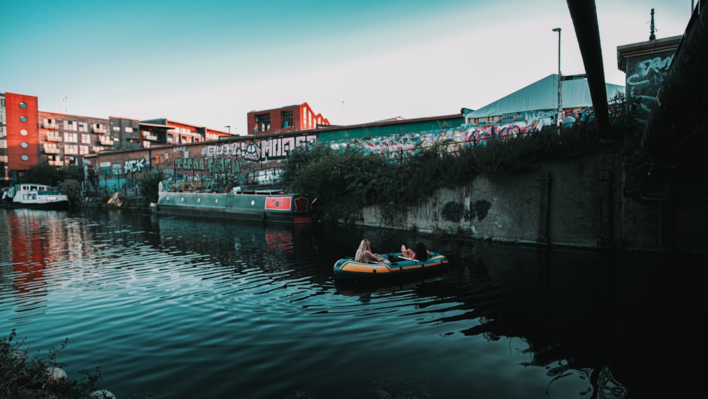 Rotes Boot auf dem Fluss in der Nähe von Betongebäude tagsüber