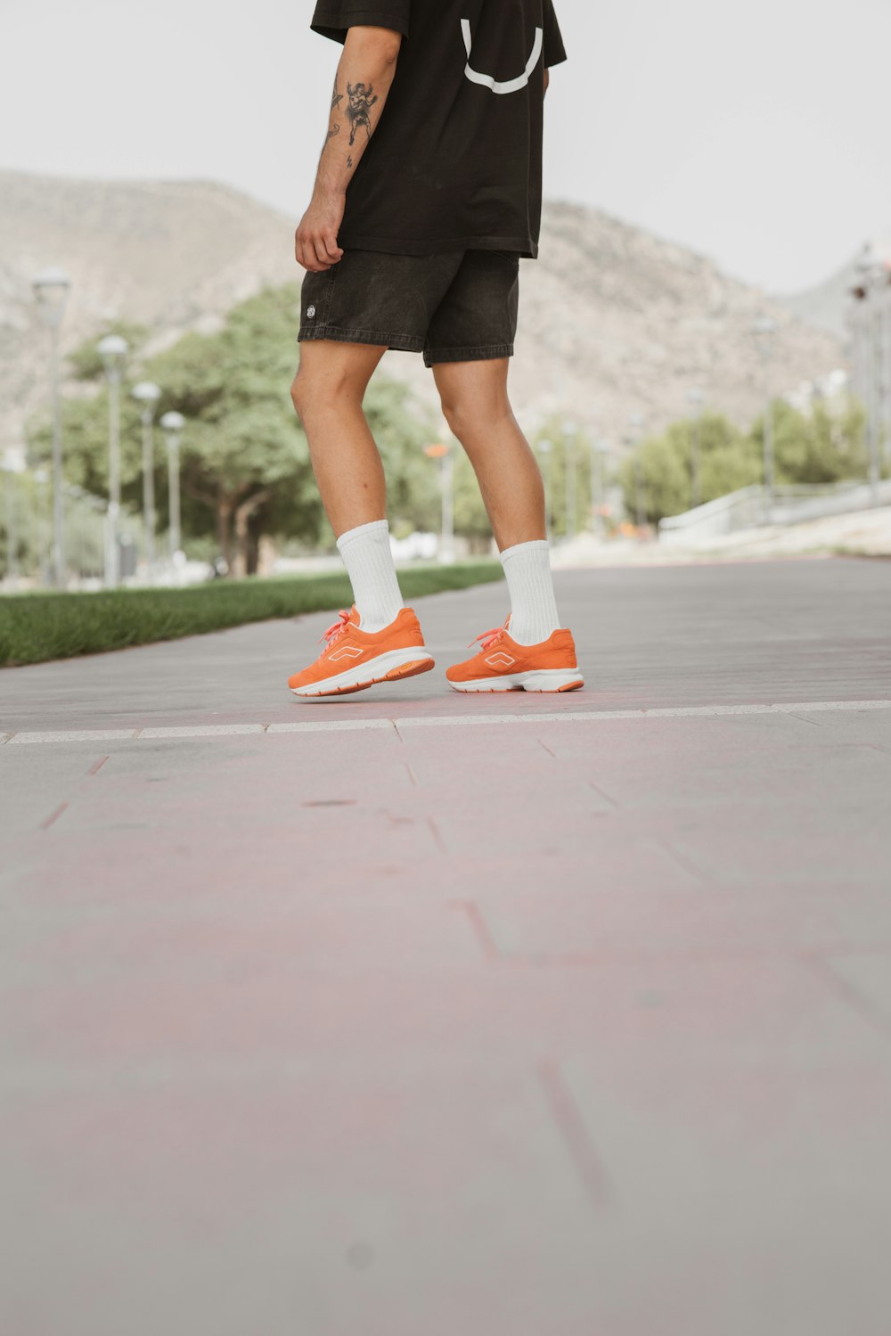 Foto Mujer con falda negra y zapatillas Nike naranjas y blancas de pie  sobre el suelo de hormigón gris durante – Imagen Zapatilla de deporte  gratis en Unsplash