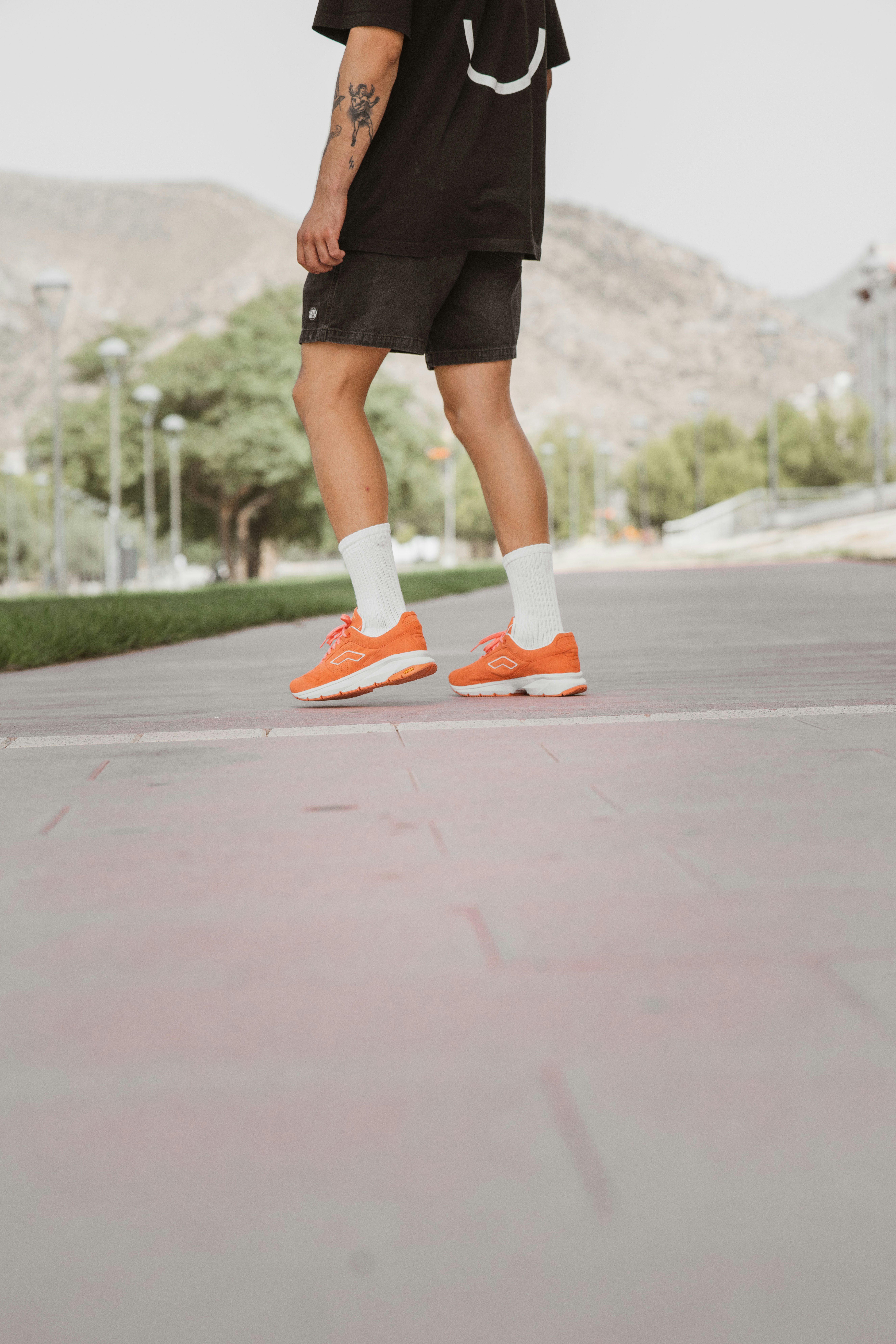 woman in black skirt and orange and white nike sneakers standing on gray concrete floor during