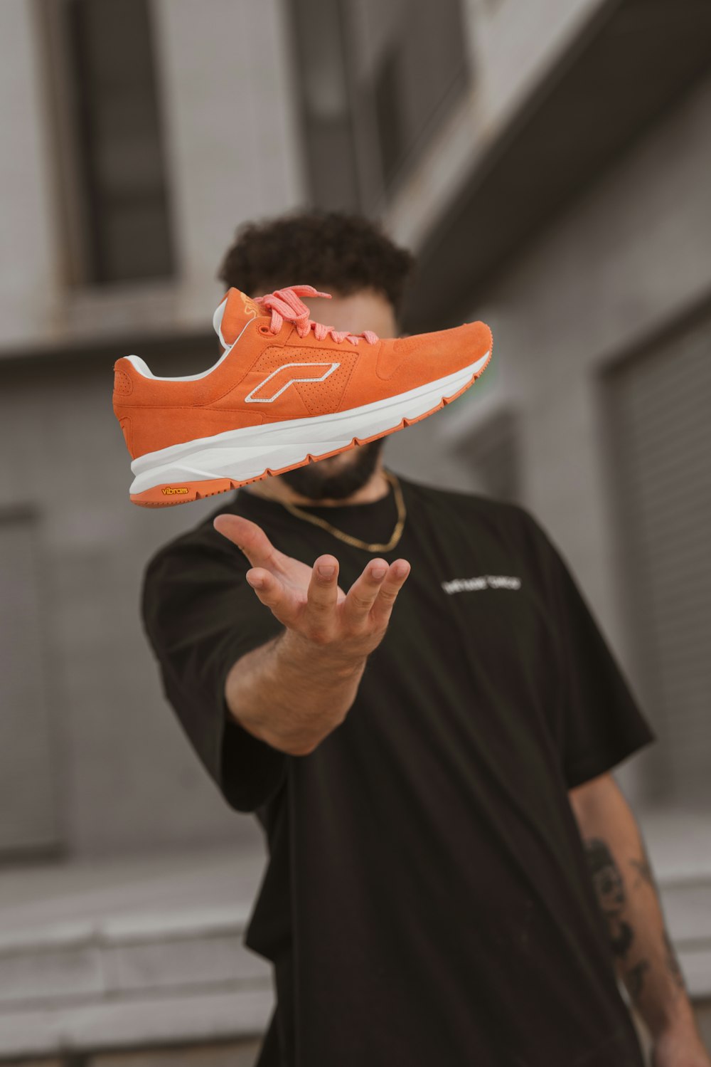 person in black shirt holding orange and white nike athletic shoe