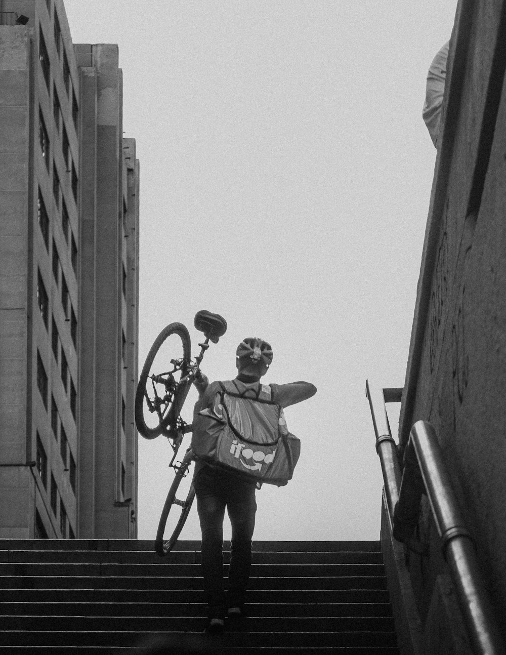 man in black and white jacket and black pants standing on black metal railings