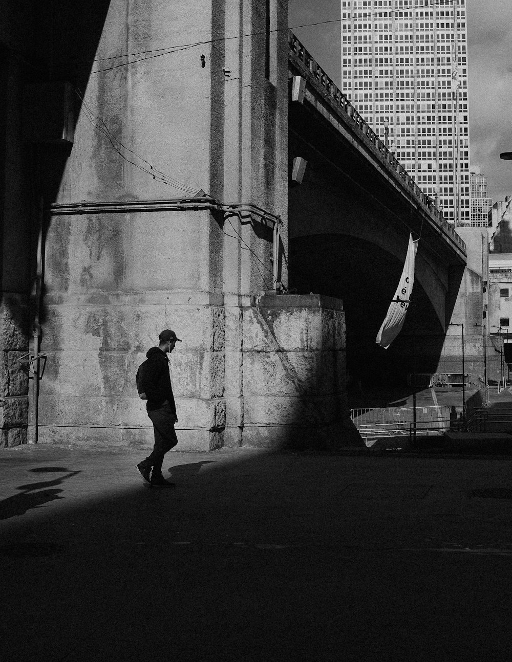 grayscale photo of man walking on sidewalk