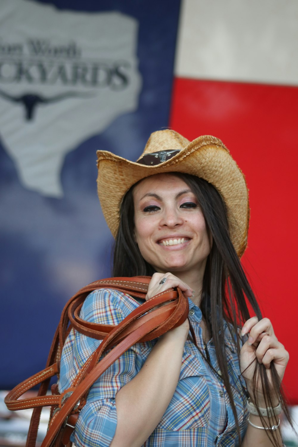 a woman wearing a cowboy hat and holding a brown bag