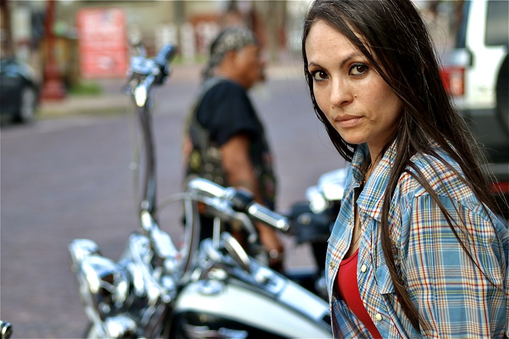 a woman standing next to a parked motorcycle