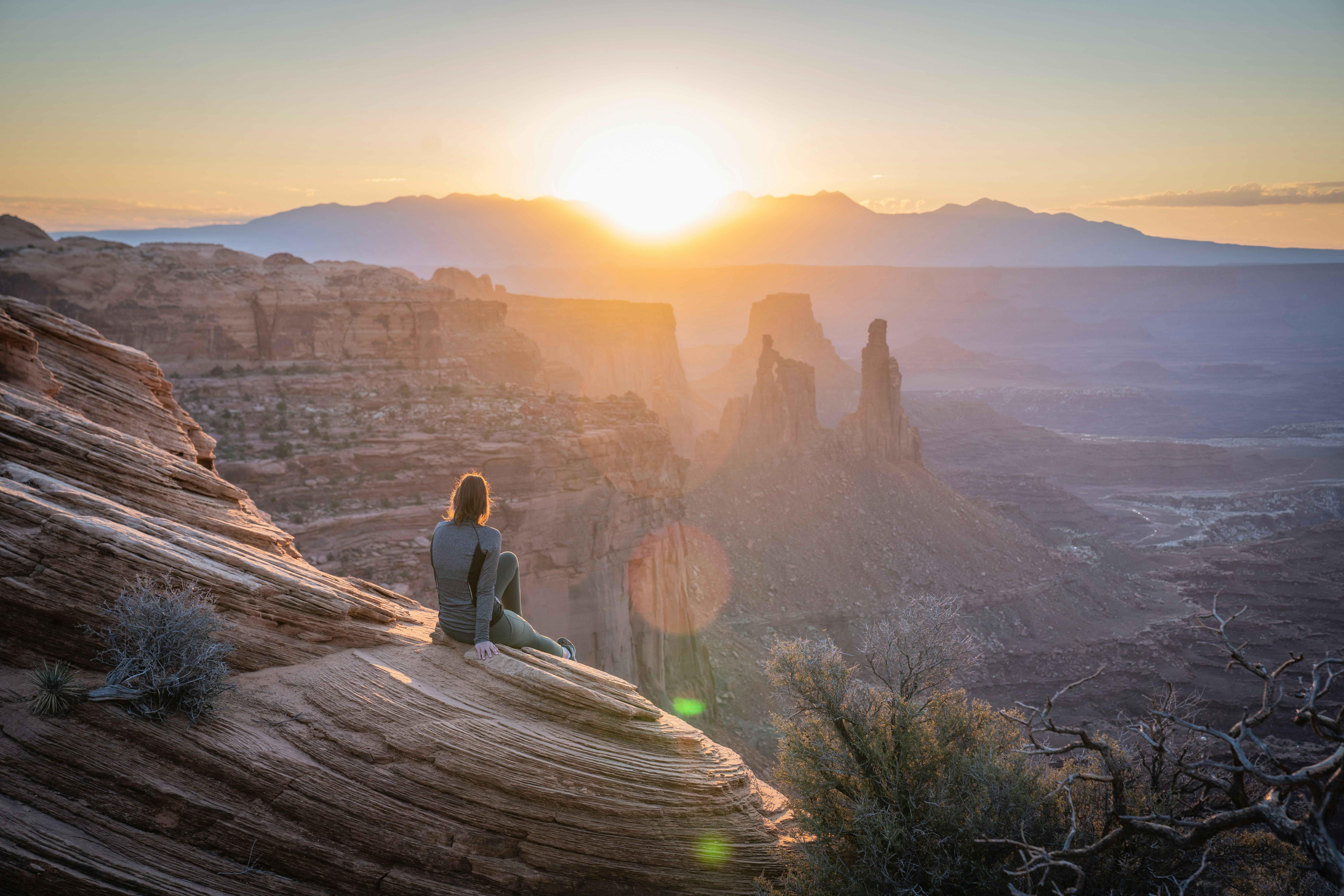 woman in gray long sleeve shirt sitting on brown rock formation during daytime, 