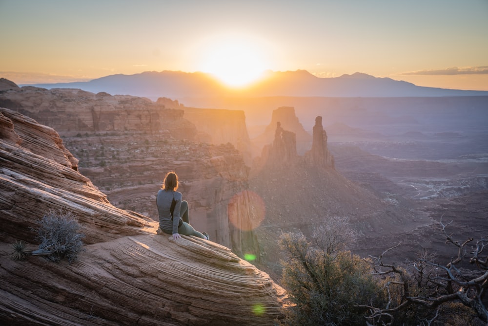 woman in gray long sleeve shirt sitting on brown rock formation during daytime