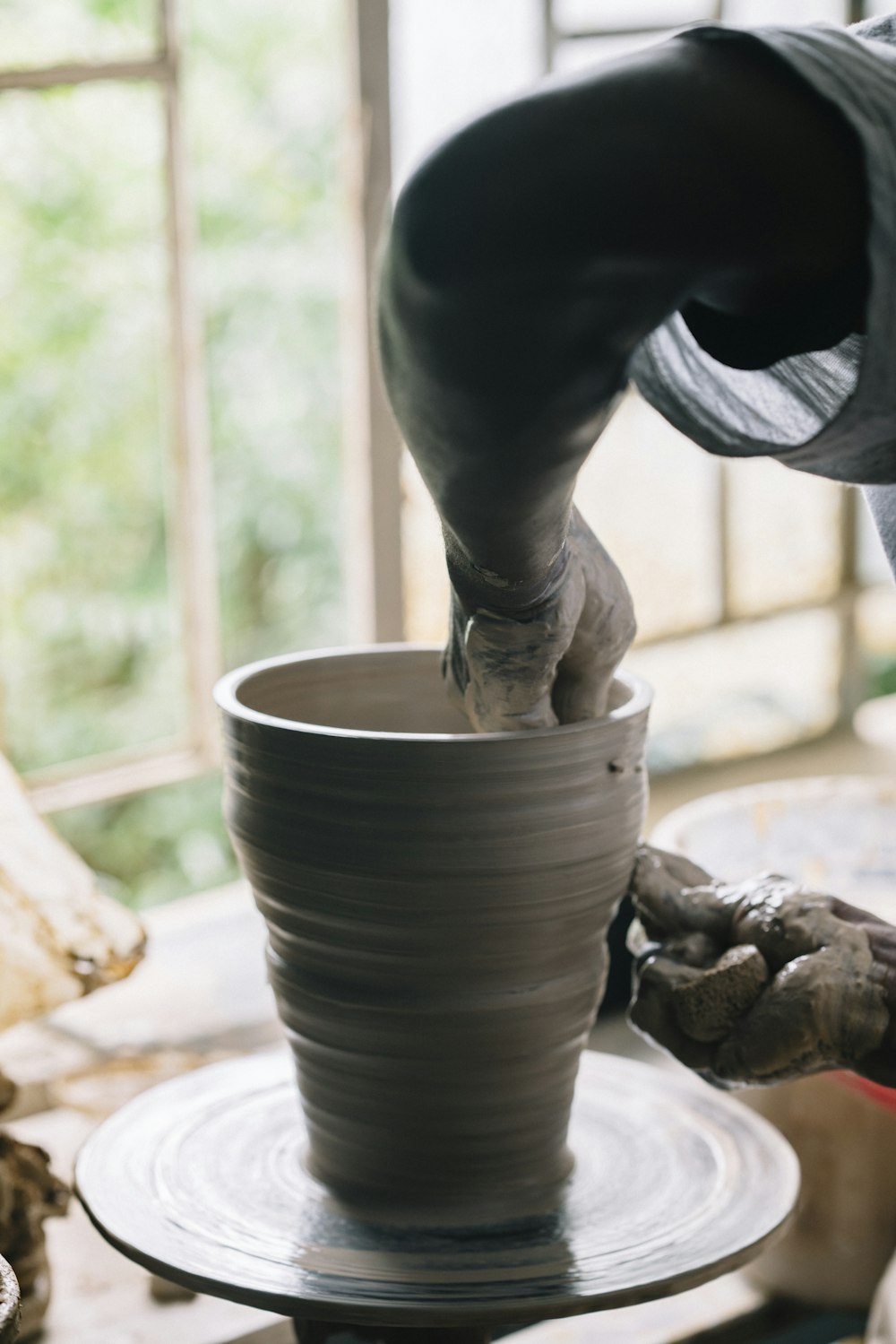 person in black gloves holding brown clay pot