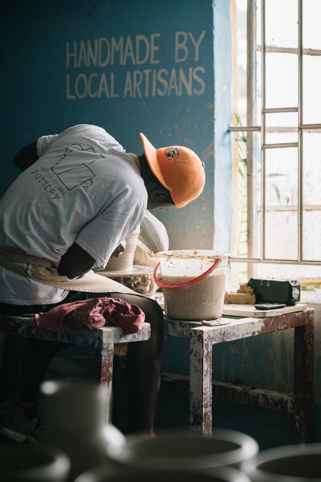  man in gray t shirt and orange cap sitting on chair pot container utensils