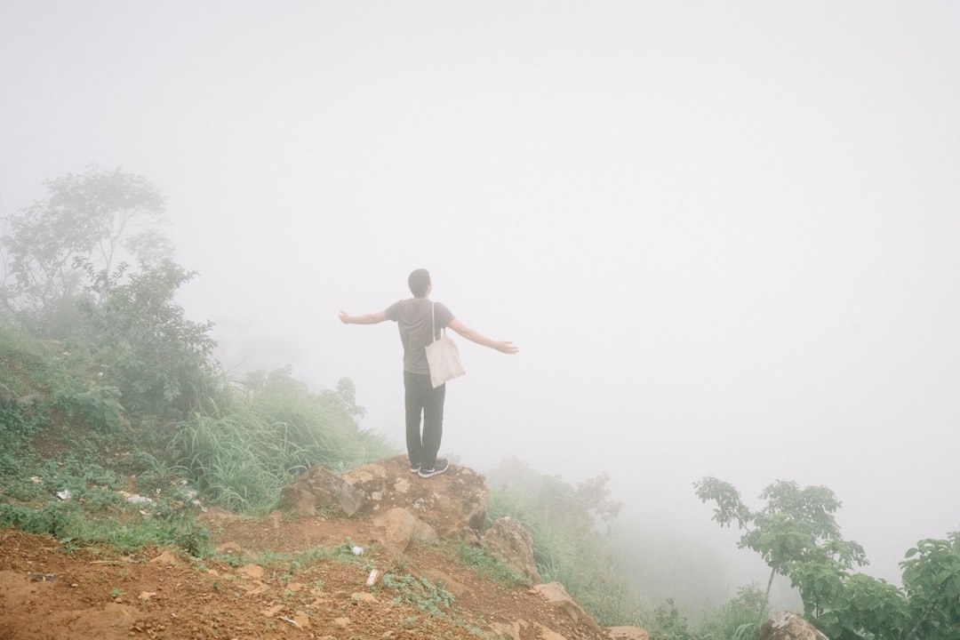 man in black shirt and black pants standing on brown rock during daytime