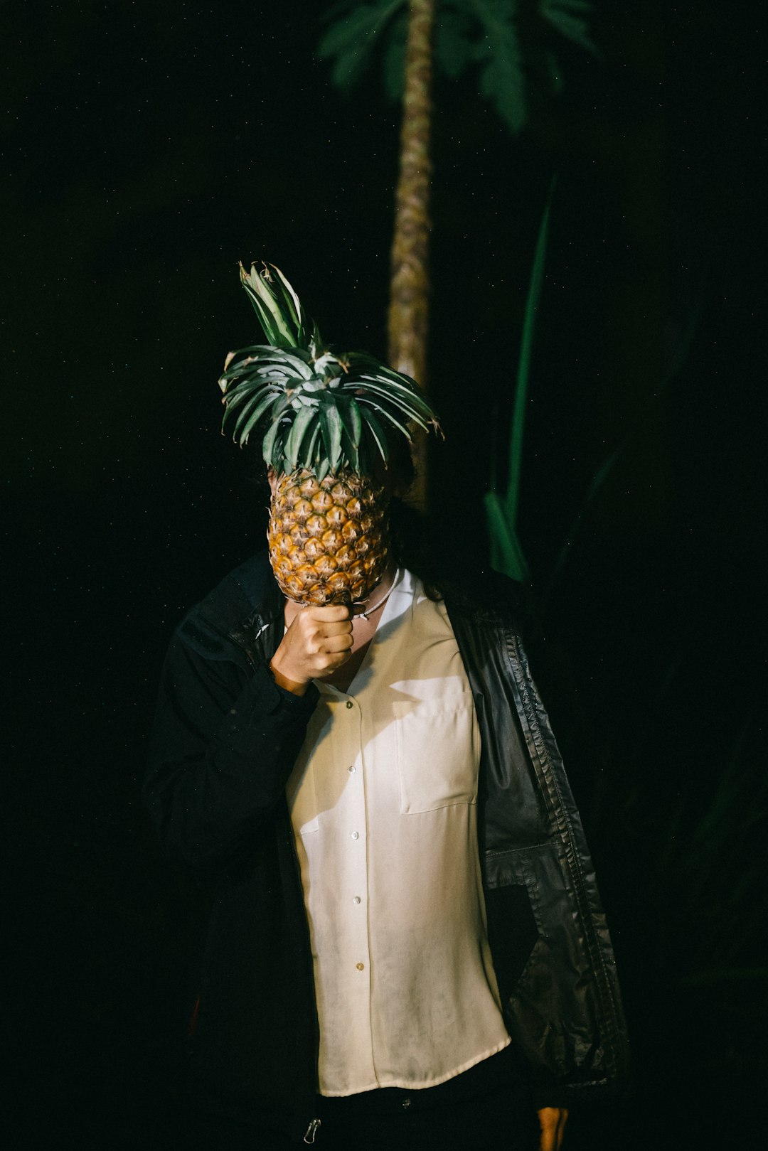 man in black jacket and white dress shirt holding pineapple