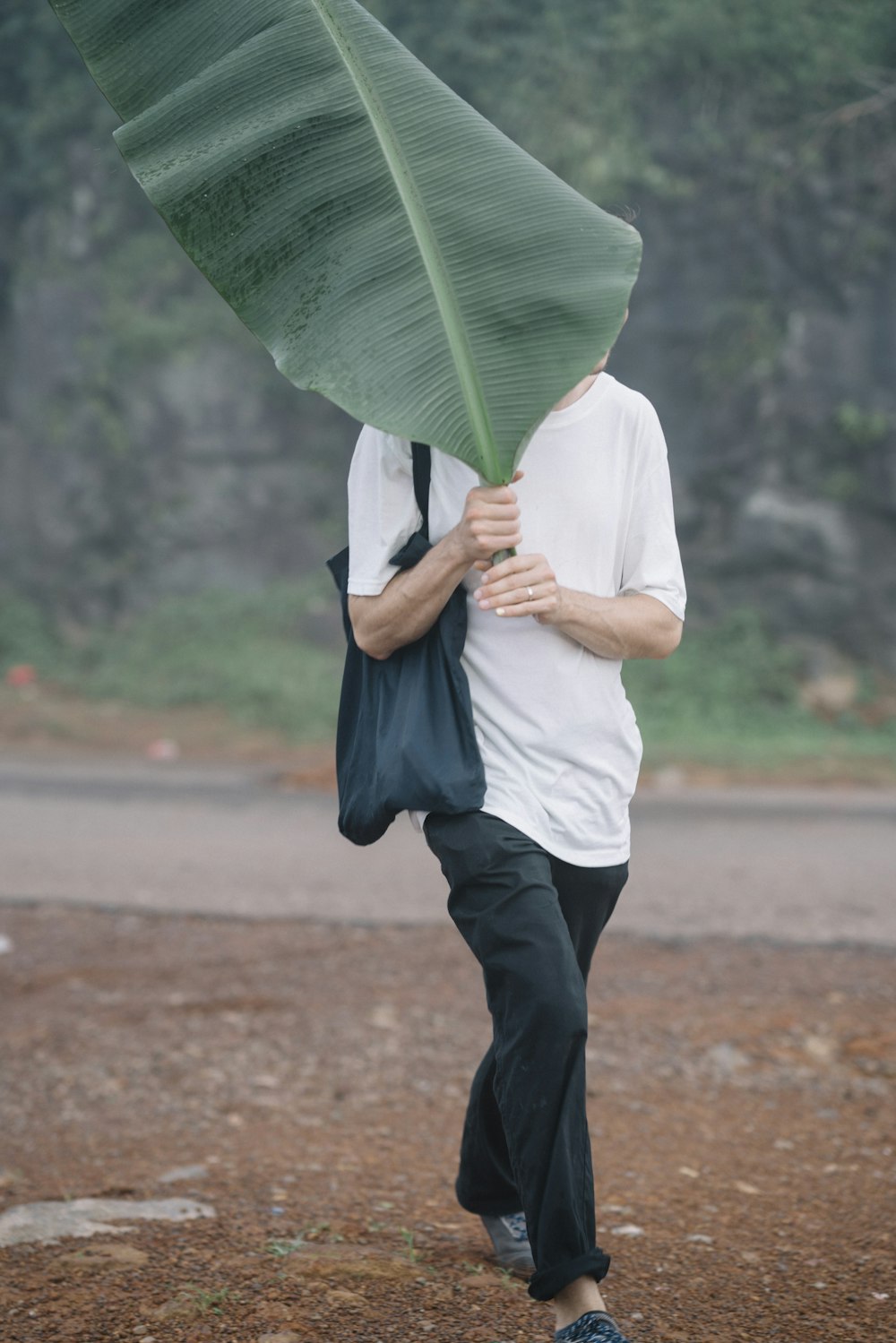 person in white shirt and black pants holding green umbrella