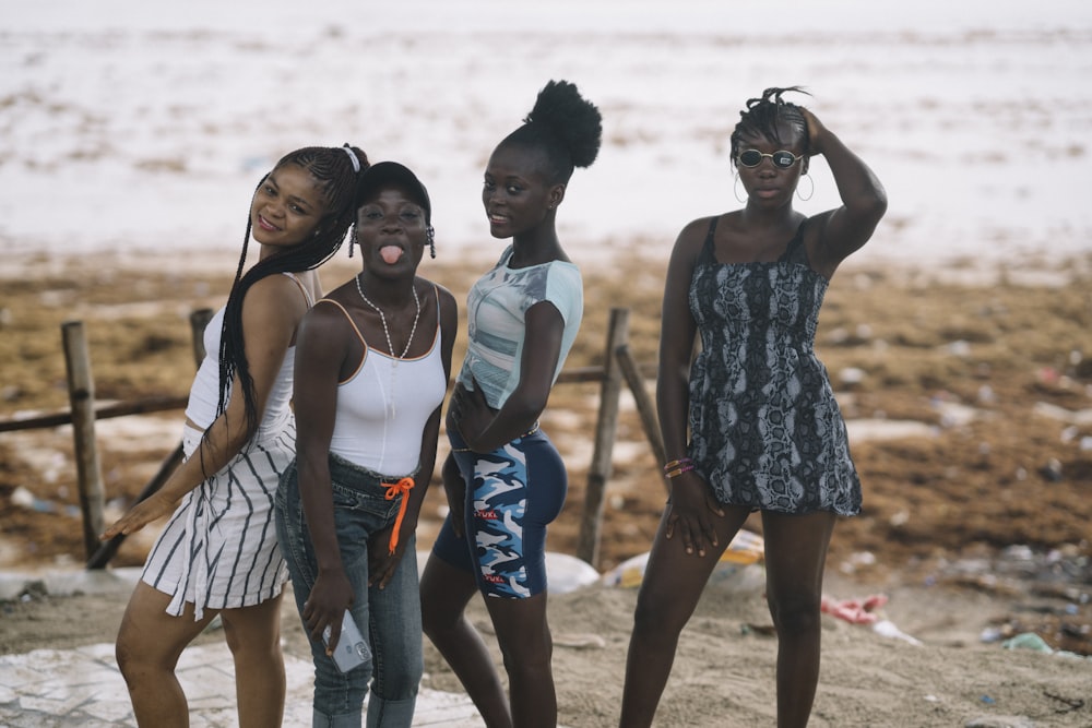 3 women standing on beach during daytime