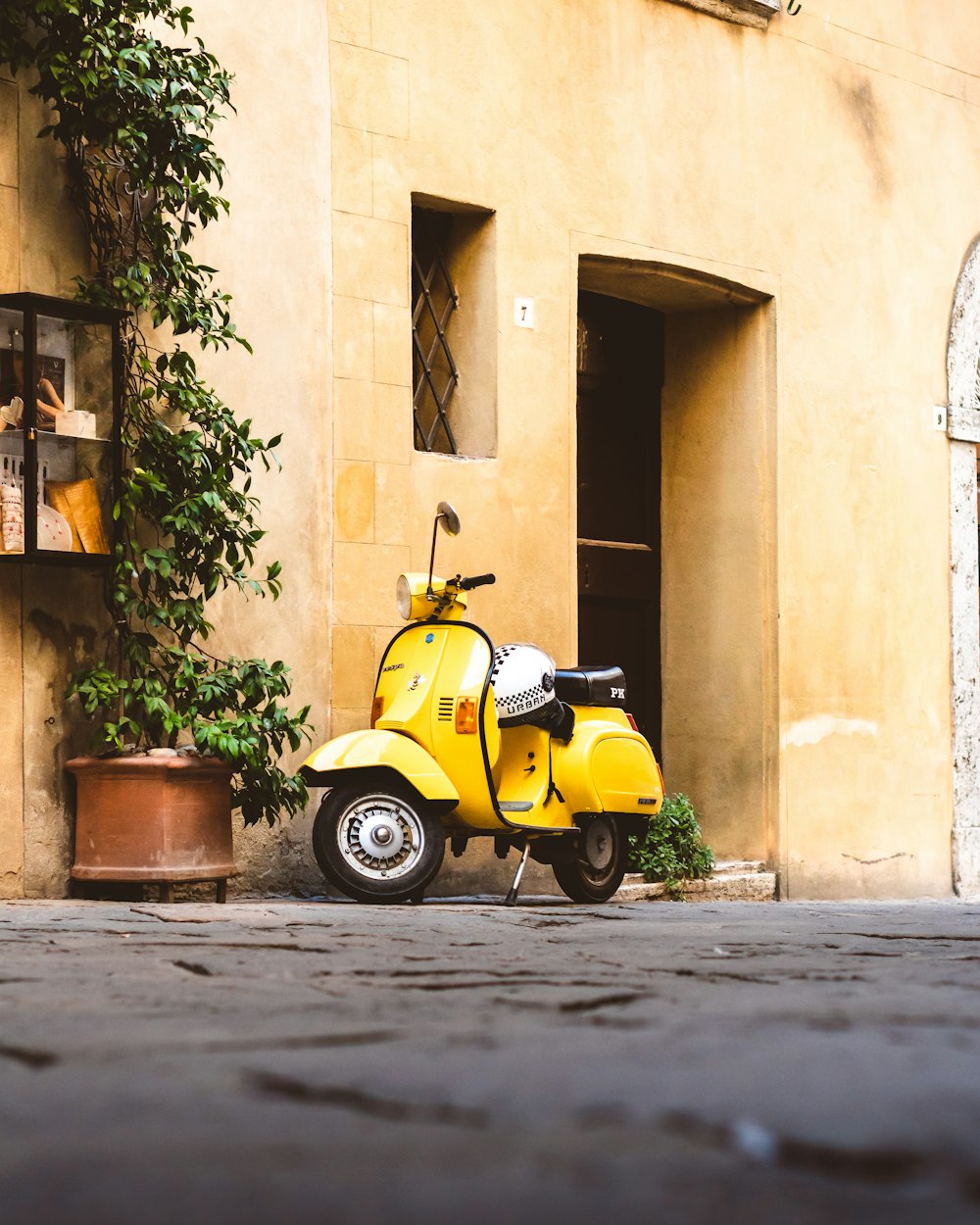 Scooter amarillo y negro estacionado junto a un edificio de concreto marrón durante el día