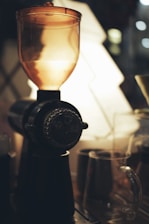 Close-up of a sleek green and purple grinder on a wooden table with soft natural light.