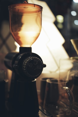 Close-up of a sleek green and purple grinder on a wooden table with soft natural light.