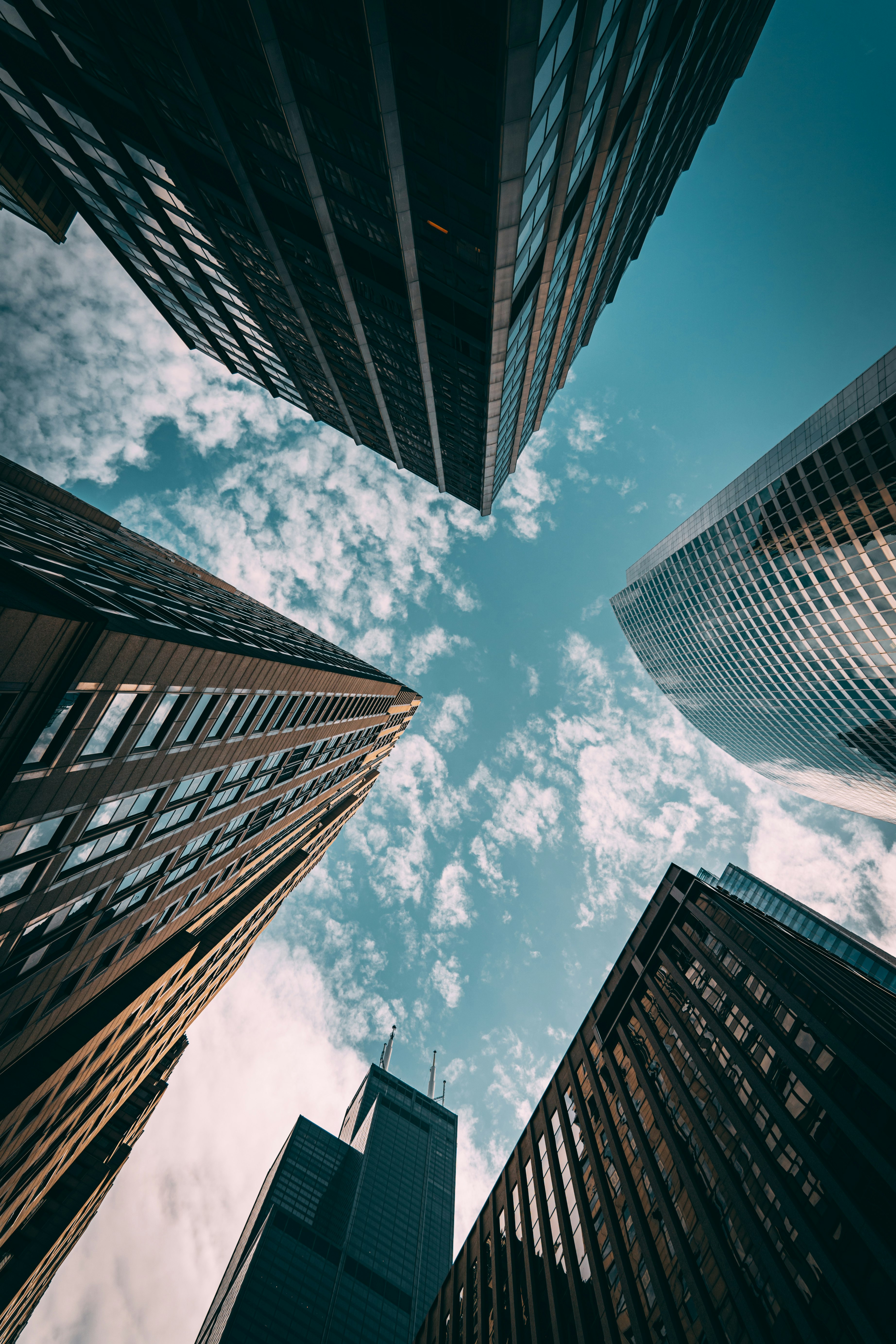 worms eye view of brown concrete building under blue and white sunny cloudy sky