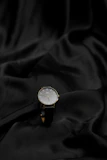 Minimalist black watch and sleek sunglasses arranged on a cream fabric