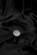 Minimalist black watch and sleek sunglasses arranged on a cream fabric