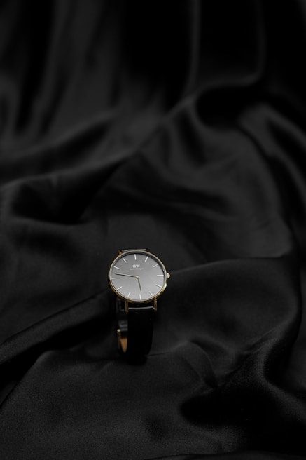 An elegant watch with a minimalist design displayed on a black velvet cushion