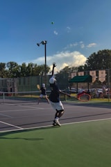 A lively tennis match in progress with players mid-swing on a sunny outdoor court.