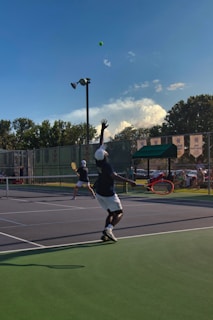 A lively tennis match in progress with players mid-swing on a sunny outdoor court.
