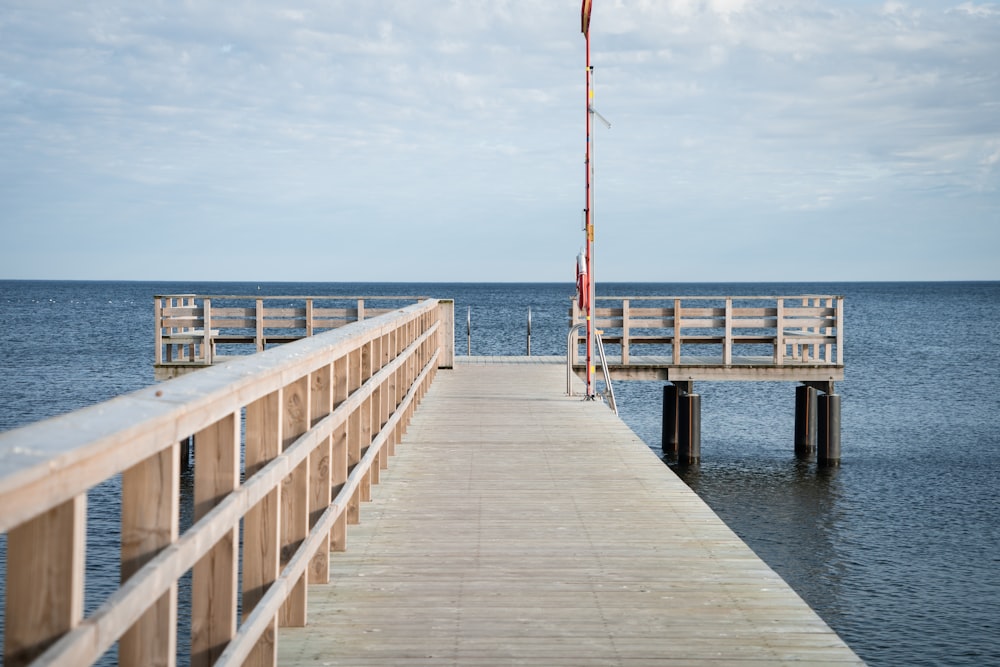 brown wooden dock on sea under white clouds during daytime