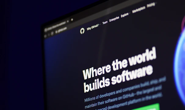 A computer screen displays a website with the text 'Where the world builds software' prominently featured. Below the text, there are fields for users to input their email address, along with additional descriptions about the platform and its capabilities. The website has a dark background with bright text, indicating a professional tech-based service.