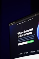 A computer screen displays a website with the text 'Where the world builds software' prominently featured. Below the text, there are fields for users to input their email address, along with additional descriptions about the platform and its capabilities. The website has a dark background with bright text, indicating a professional tech-based service.