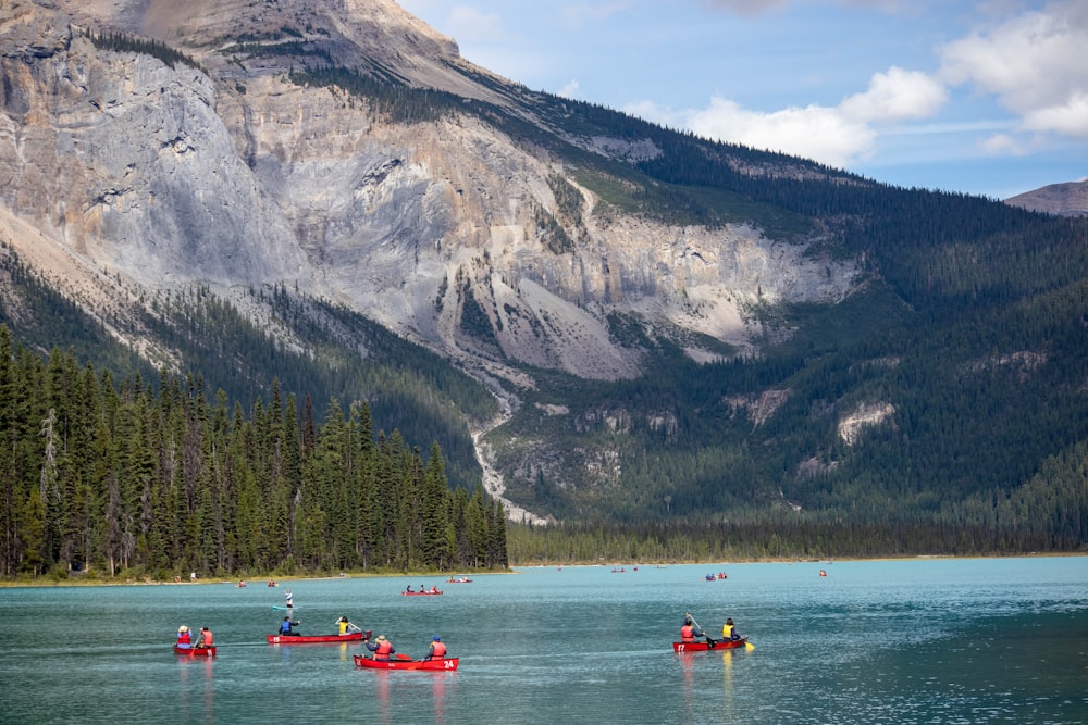 people riding on red kayak on lake near mountain during daytime
