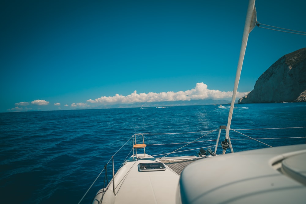 white and blue boat on sea under blue sky and white clouds during daytime