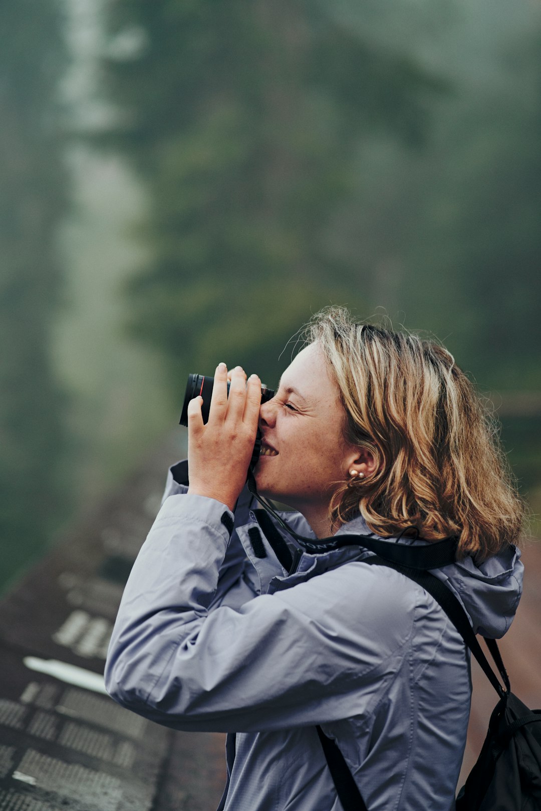 woman in gray jacket holding black smartphone