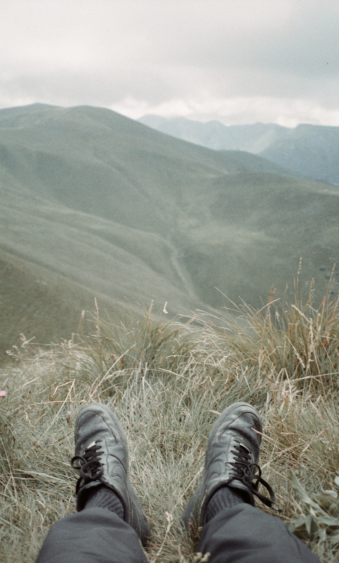 person in black pants and black shoes sitting on green grass during daytime