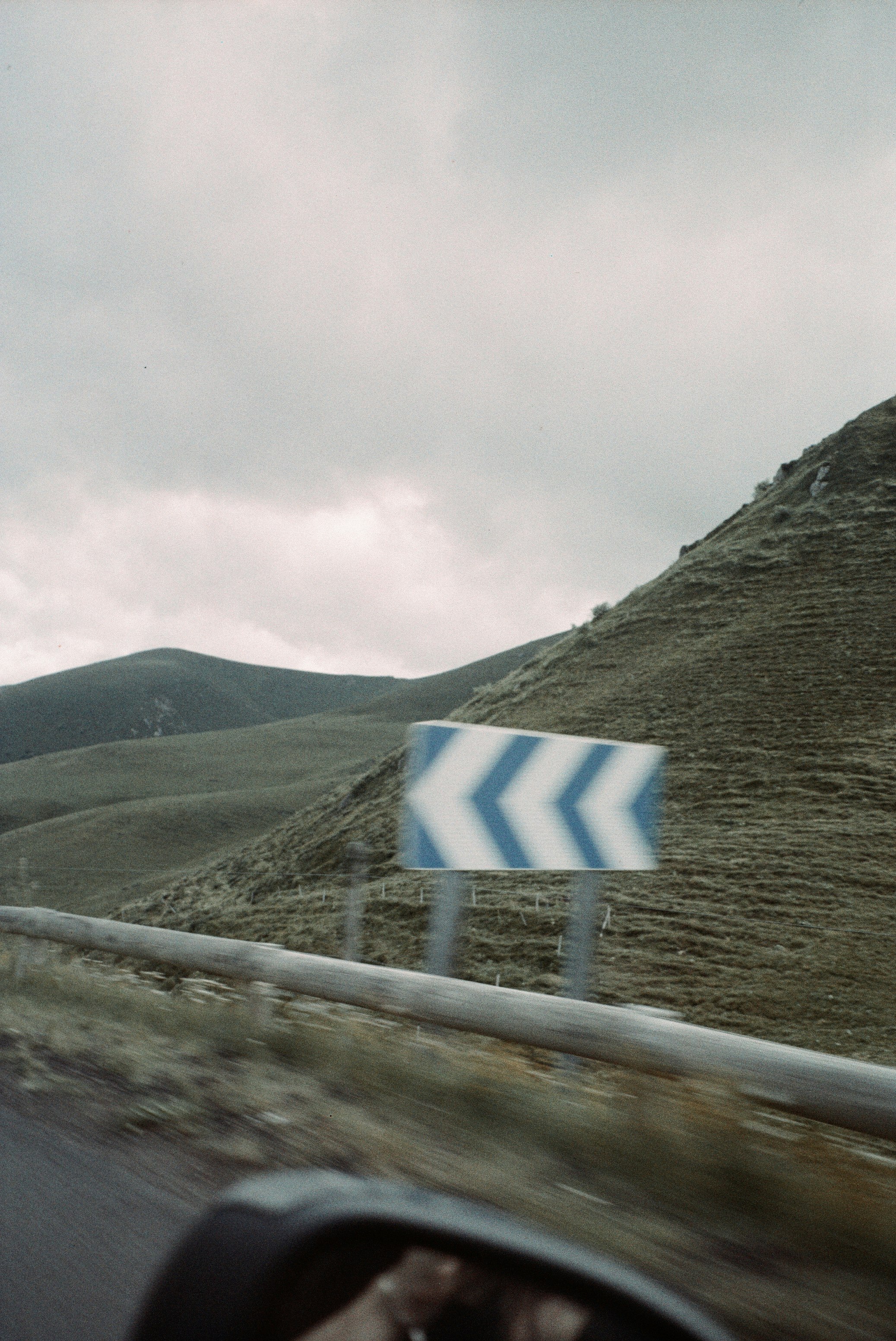 white and blue striped road sign on gray hill