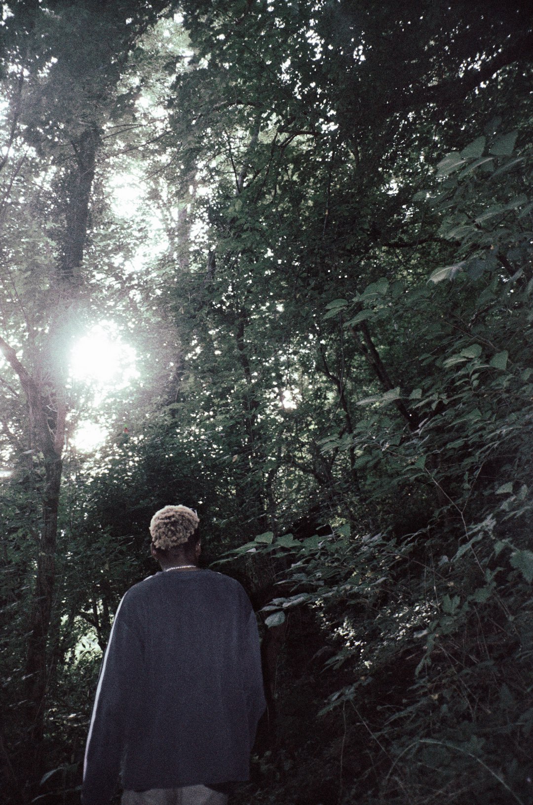 man in black suit standing in the middle of forest during daytime