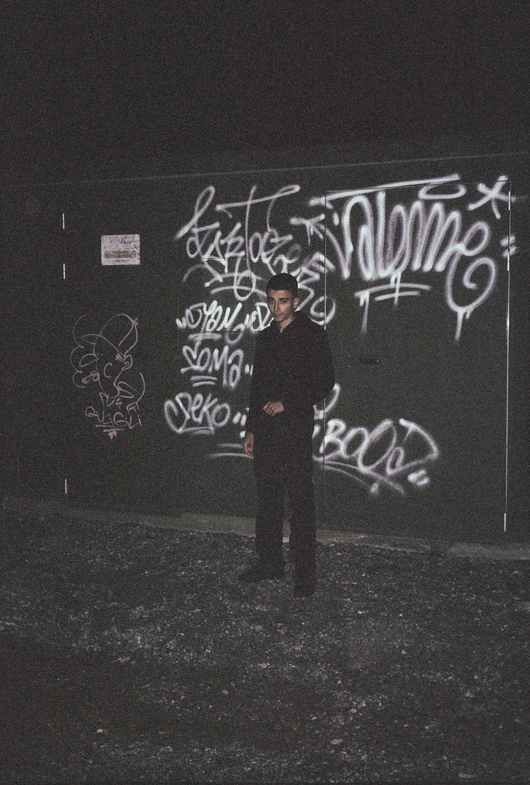 man in black coat standing near black wall