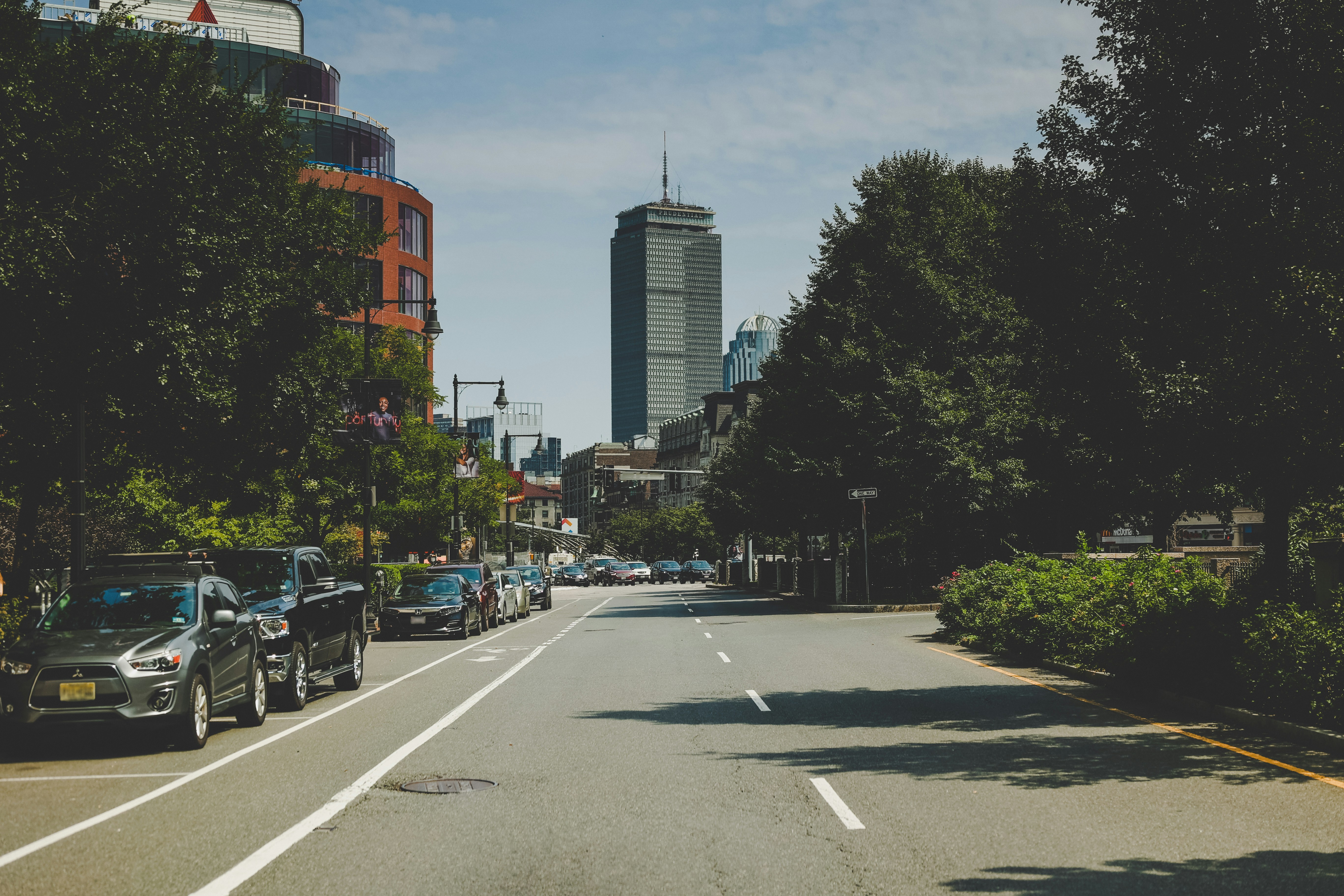 cars parked on side of the road near high rise buildings during daytime