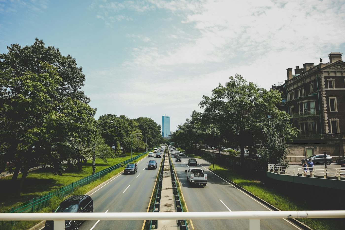 Cars on tree-lined Storrow Drive in Boston on a clear day, the last stretch when driving to Boston for medical appointments from NH