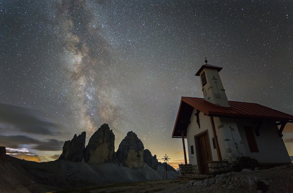 casa branca e marrom perto da montanha rochosa sob a noite estrelada