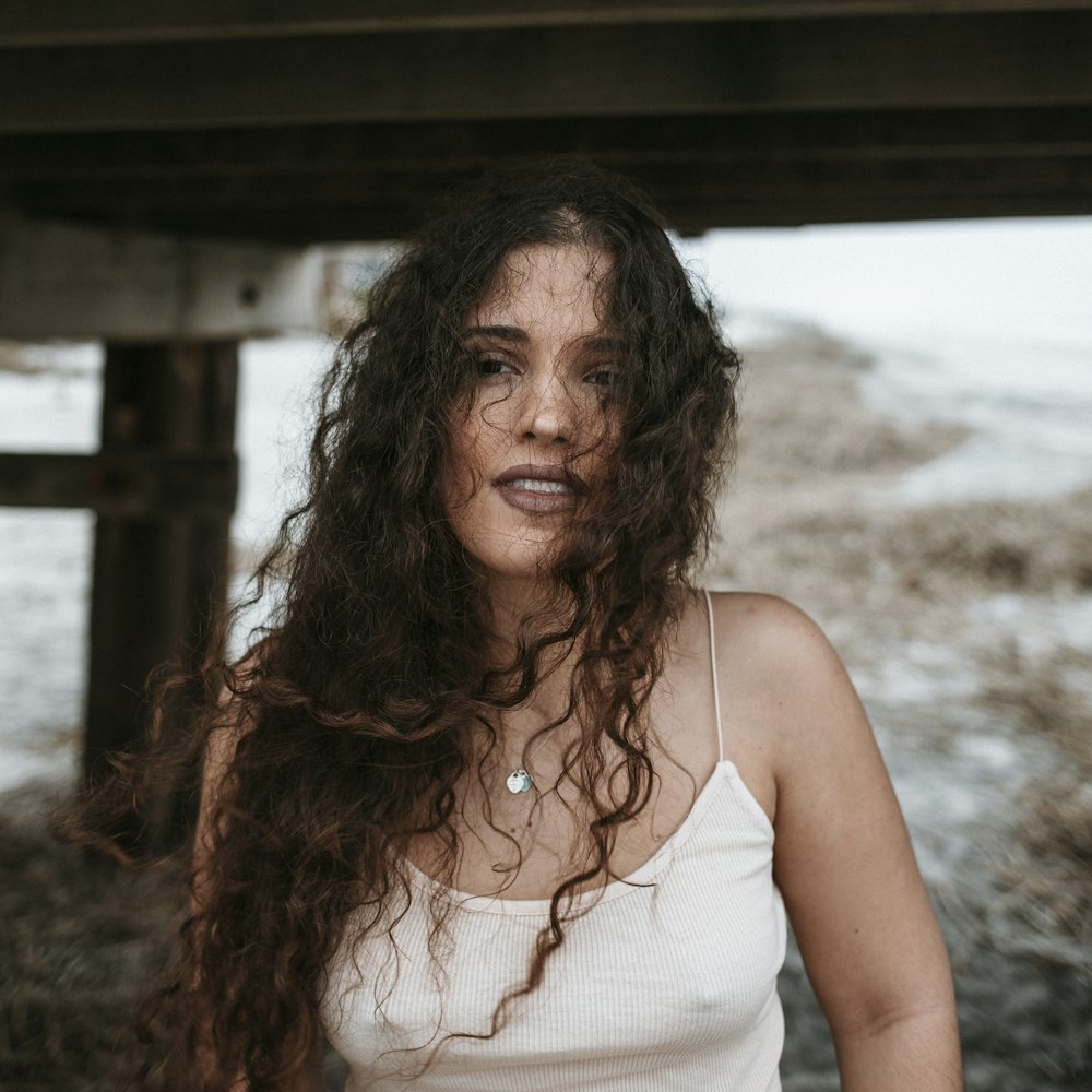 woman in white tank top standing on beach during daytime