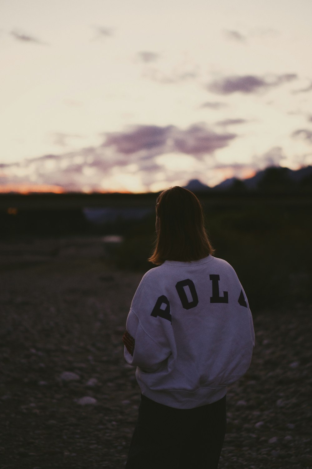 woman in white and black hoodie standing on field during daytime