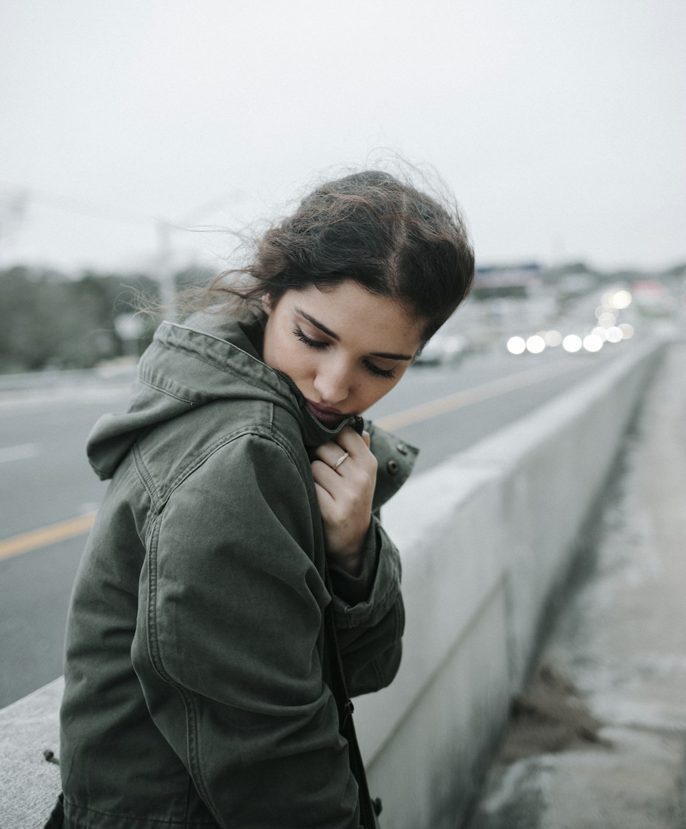 woman in green jacket holding smartphone