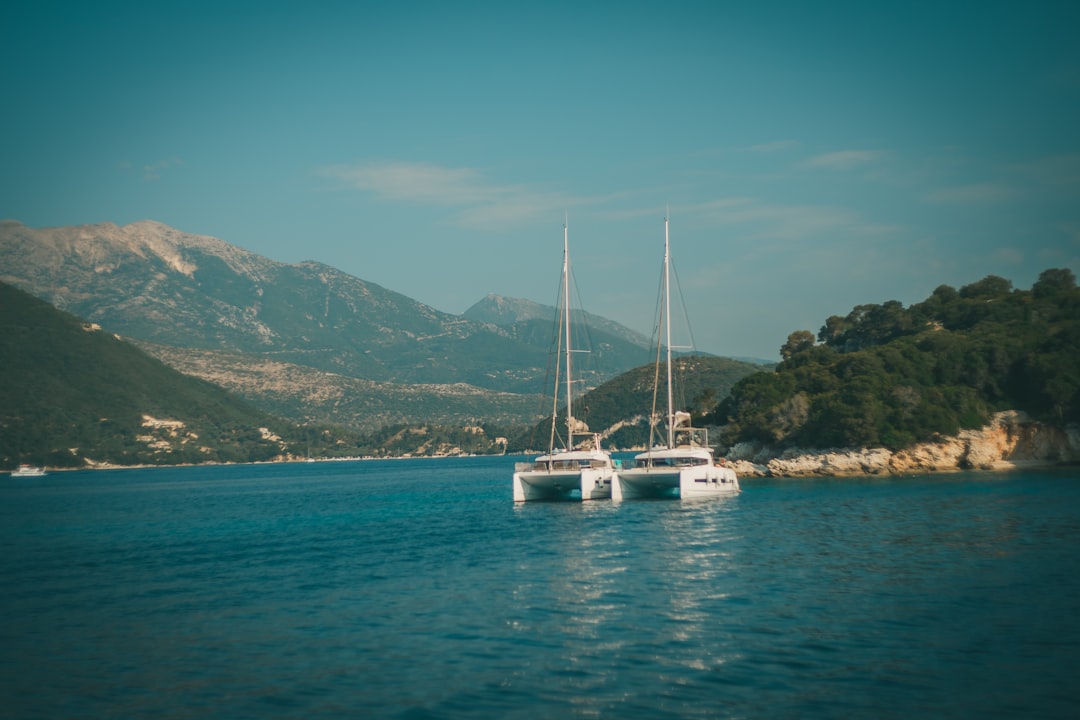 white sailboat on sea near mountain under blue sky during daytime