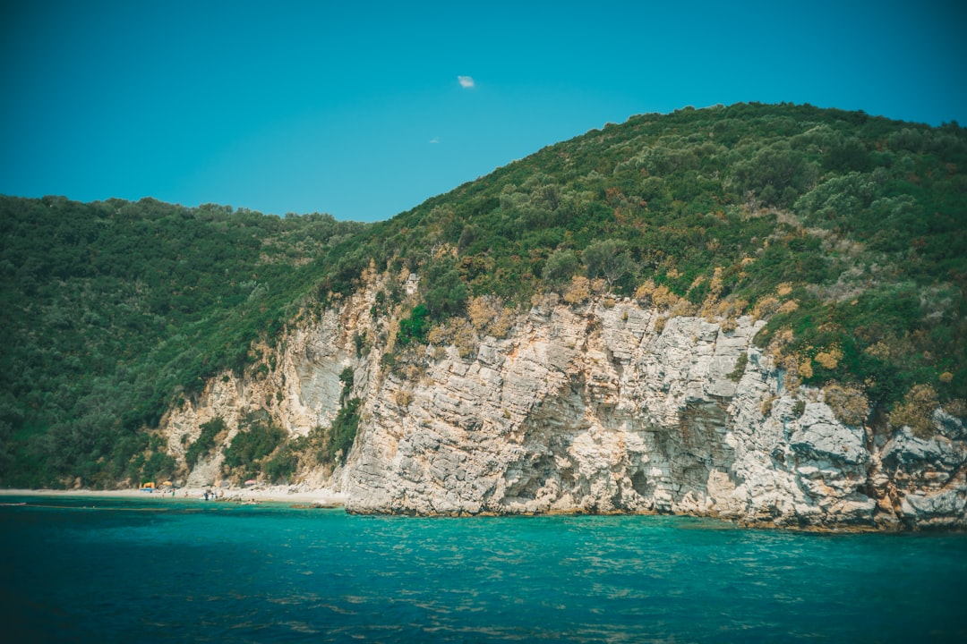 green and brown mountain beside blue sea under blue sky during daytime