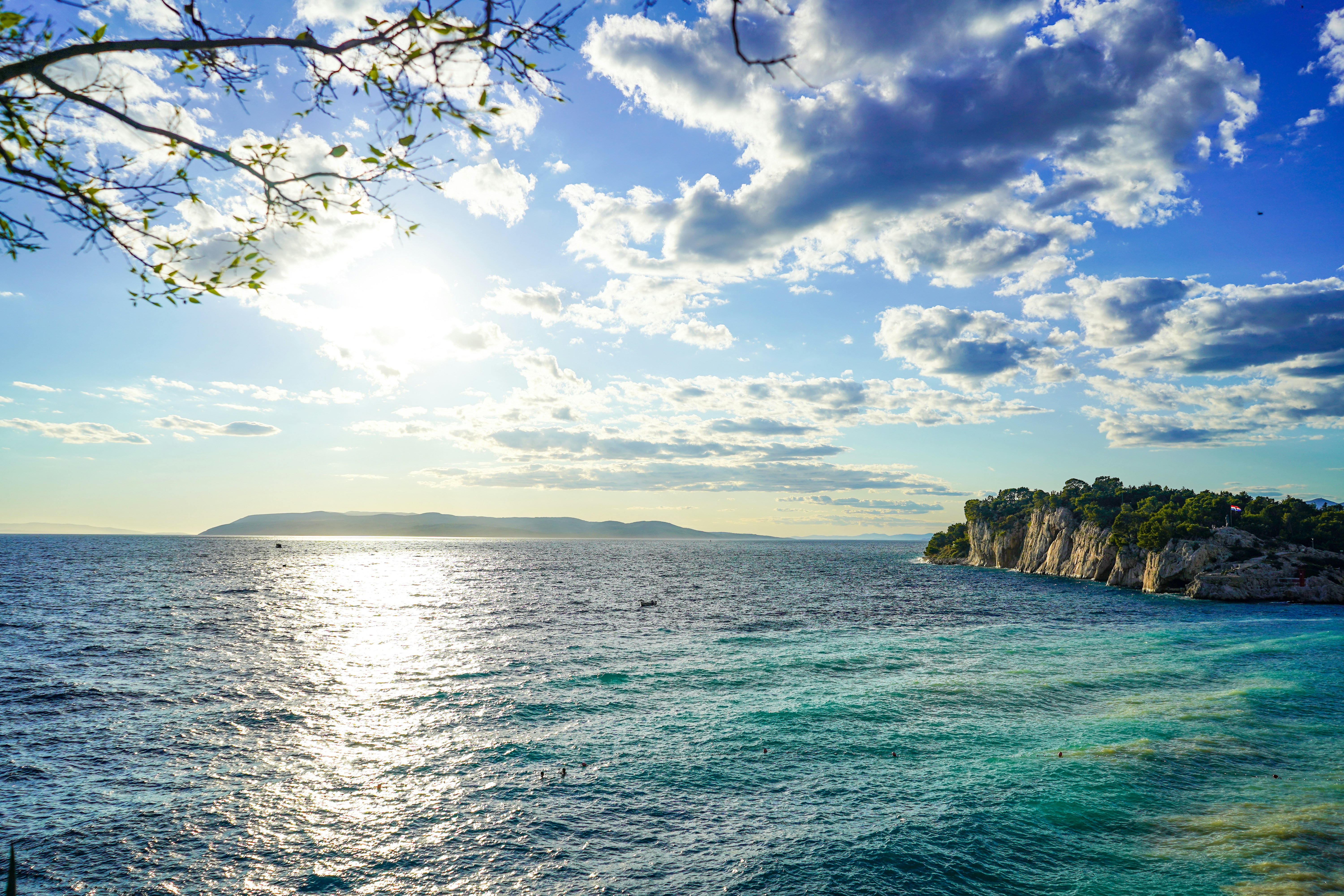 Green and brown rock formation on sea under blue and white cloudy sky during daytime