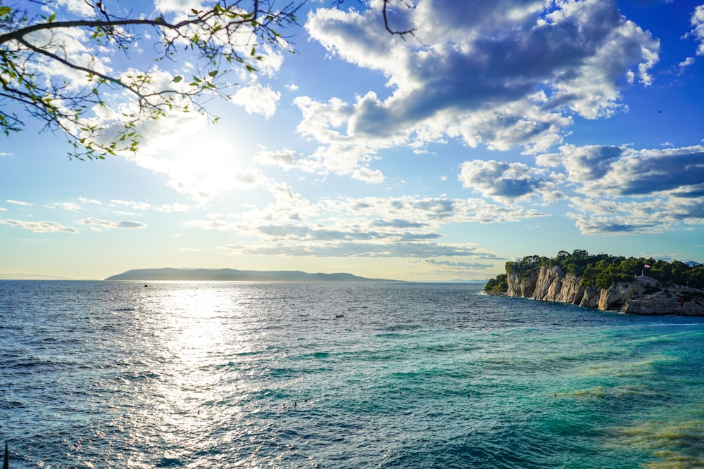 green and brown rock formation on sea under blue and white cloudy sky during daytime