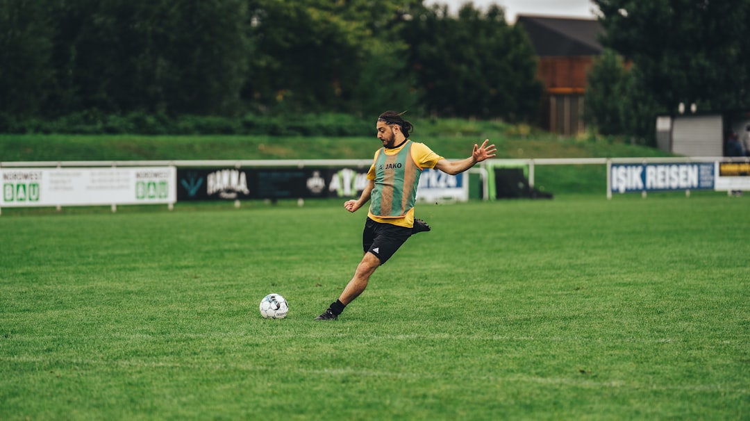 woman in yellow shirt and black shorts playing soccer during daytime