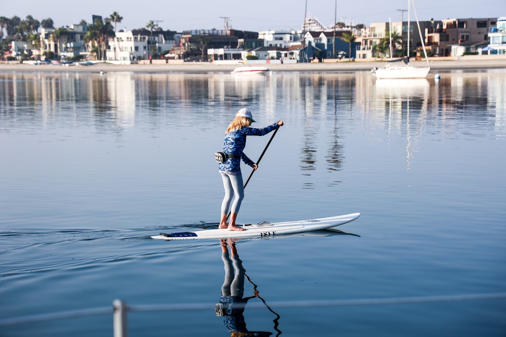 man in blue shirt riding white surfboard during daytime