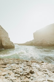 brown rocky mountain beside body of water during daytime
