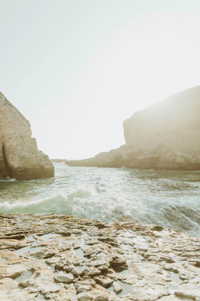 brown rocky mountain beside body of water during daytime