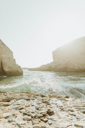 brown rocky mountain beside body of water during daytime